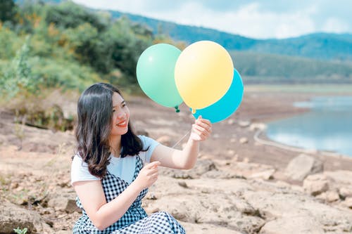 拿着三个气球的白色和黑色礼服的女人 · 免费素材图片