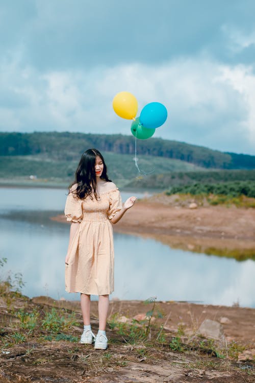 米色的露肩礼服，拿着气球的女人 · 免费素材图片