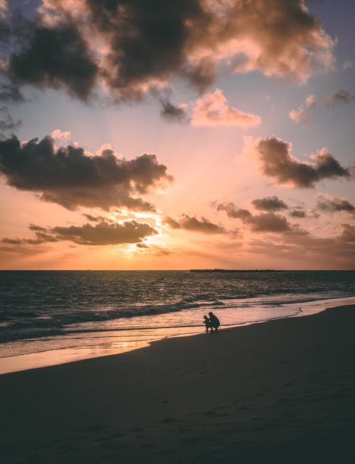 两人在海边日落期间的剪影 · 免费素材图片