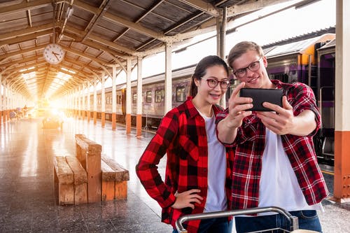 男人和女人在灰色的火车附近采取自拍照 · 免费素材图片