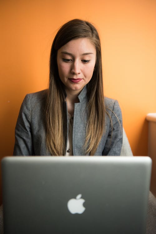 使用银苹果macbook的灰色西装外套的女人 · 免费素材图片