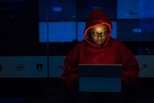 红色连帽衫使用灰色便携式计算机的女人 · 免费素材图片