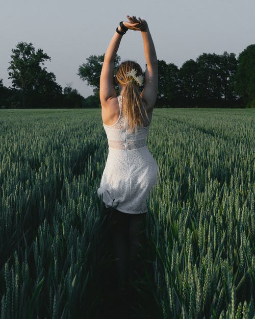 女人穿着白色蕾丝连衣裙用手在头顶举起 · 免费素材图片