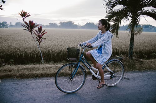 骑在蓝色和白色的自行车上的女人 · 免费素材图片