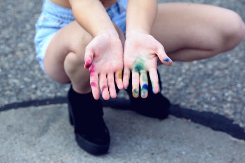 女人蹲着伸出她的手与各类涂料 · 免费素材图片