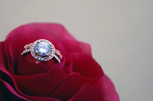 红玫瑰上的透明珠宝金色簇状戒指的特写摄影 · 免费素材图片