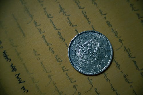 棕色打印机纸上的圆形银色硬币 · 免费素材图片