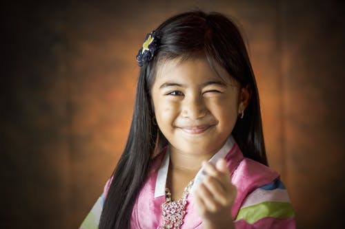 微笑的女孩做手指心脏标志 · 免费素材图片