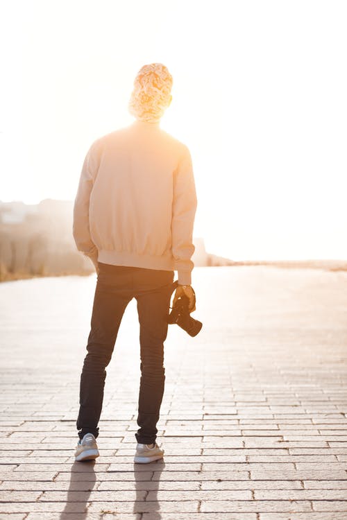 男孩站在白天时按住相机俯瞰阳光 · 免费素材图片