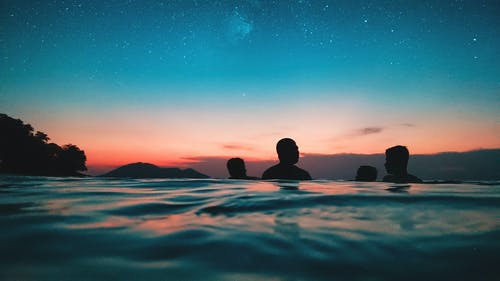 人在黄昏时在水面上的剪影 · 免费素材图片