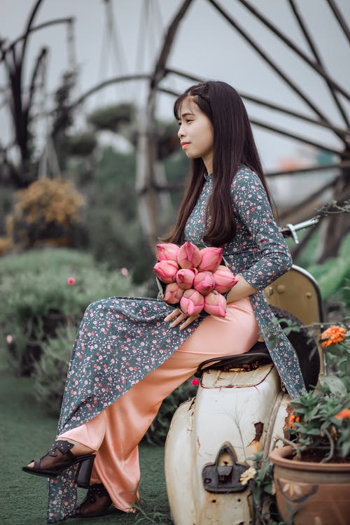 女人坐在摩托车上，按住香蕉花花束 · 免费素材图片