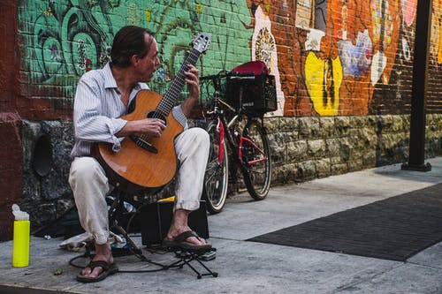 人坐在街上弹棕色古典吉他 · 免费素材图片