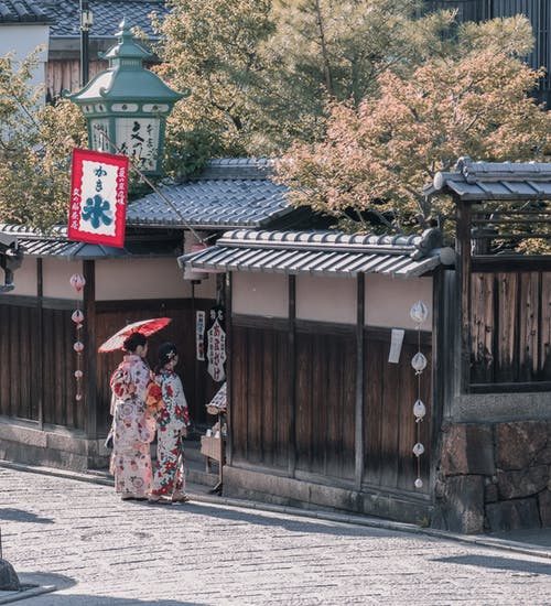 两名身穿传统服装的妇女站在房子附近 · 免费素材图片