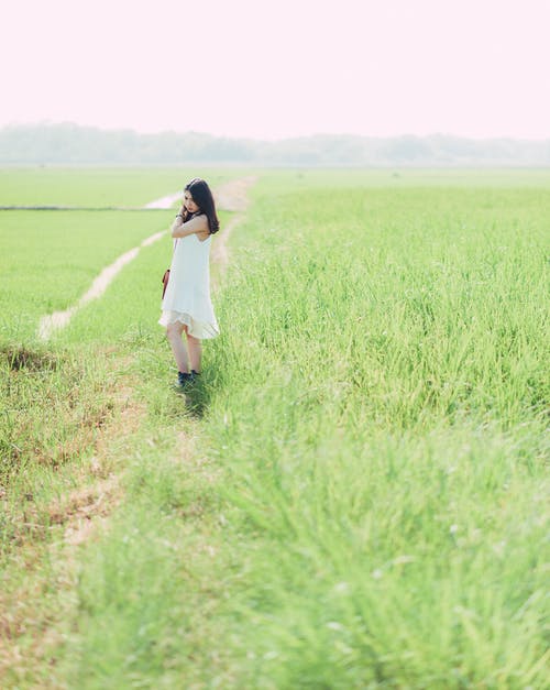 站在绿草地上的白色连衣裙的女人 · 免费素材图片