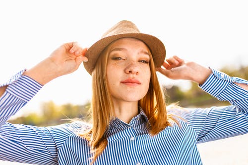 女人穿着棕色的帽子和蓝色条纹的衬衫 · 免费素材图片