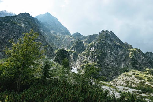 绿树和多云的天空下的山 · 免费素材图片