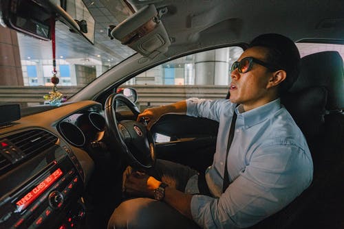 男子身穿浅蓝色纽扣式正装衬衫驾驶车辆 · 免费素材图片