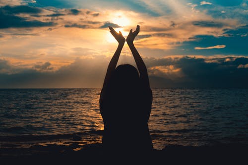 在日落时在海边举手的人 · 免费素材图片