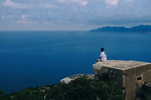 男子坐在屋顶的边缘 · 免费素材图片