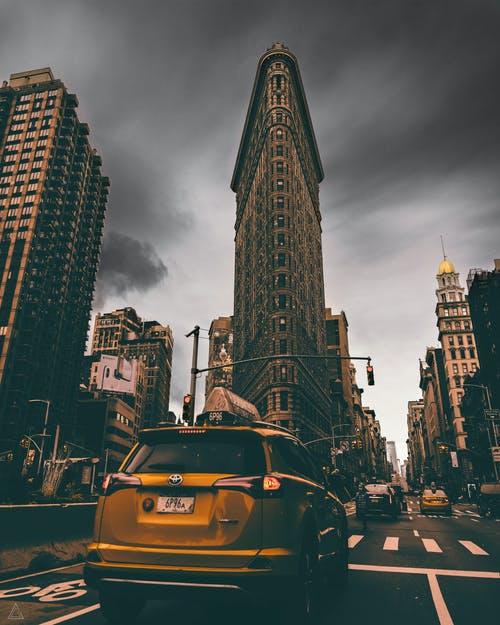 黄色丰田rav4 Suv在纽约熨斗大厦附近的道路上奔跑 · 免费素材图片