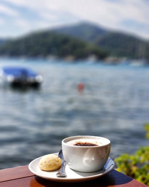 白色陶瓷茶杯在水面上的飞碟上的特写照片 · 免费素材图片