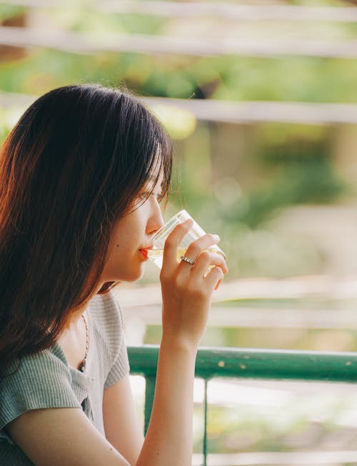 女人在金属栅栏附近喝酒的选择性聚焦摄影 · 免费素材图片