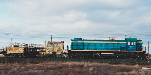 田野旁边的蓝色和棕色火车 · 免费素材图片