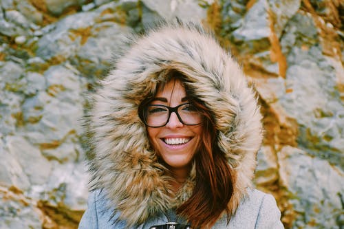 女人在岩层附近微笑时戴眼镜 · 免费素材图片