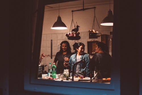 三个女人站在房间里的灯打开 · 免费素材图片