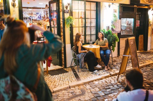 两个男人和女人拍照的两个女人坐在和谈与菜单板路旁的圆桌旁 · 免费素材图片