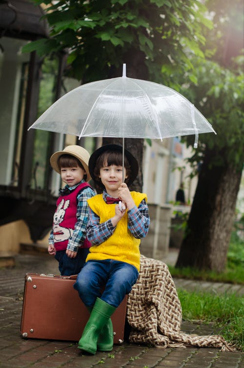 坐在棕色手提箱上的女孩拿着伞 · 免费素材图片