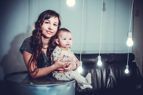 白色led灯泡旁边的女人抱着婴儿 · 免费素材图片