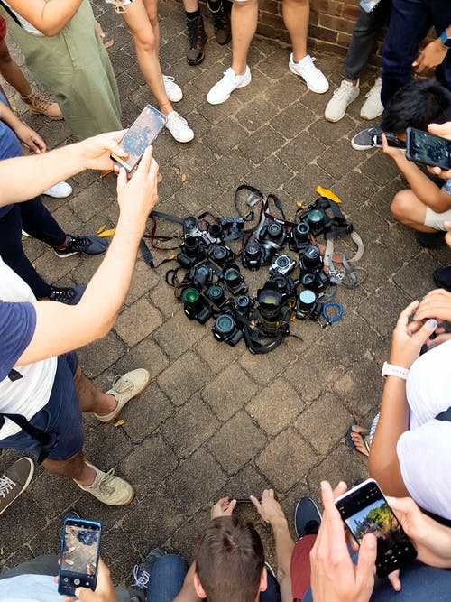 数码单反相机躺在被人包围的地面上的照片 · 免费素材图片