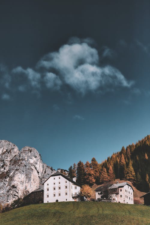 多云的天空下山旁边的建筑物 · 免费素材图片