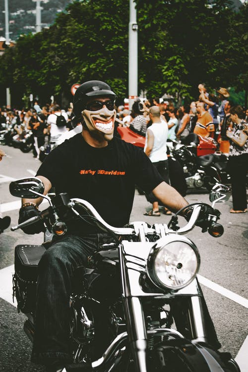 戴着面具的男子骑摩托车的照片 · 免费素材图片