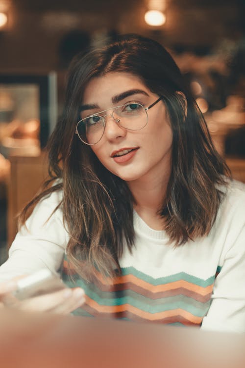女人坐在一家咖啡店的眼镜的特写照片 · 免费素材图片