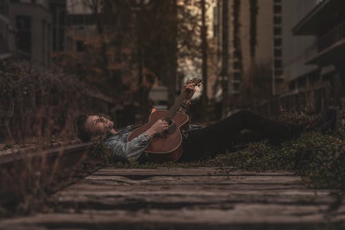 弹吉他时躺在地上的人 · 免费素材图片