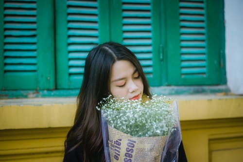 女人抱着白花花束 · 免费素材图片