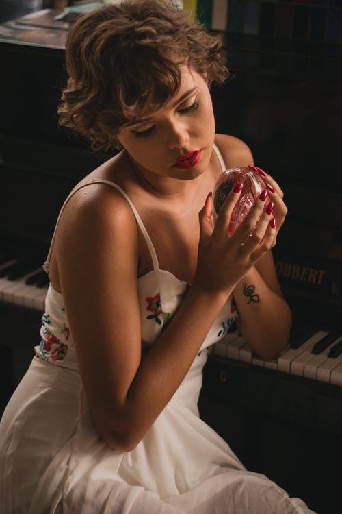 女人抱着坐在钢琴旁边的水晶球 · 免费素材图片