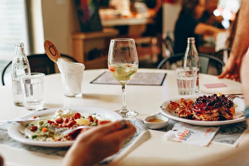 在透明玻璃酒在桌子上的盘子附近的食物 · 免费素材图片
