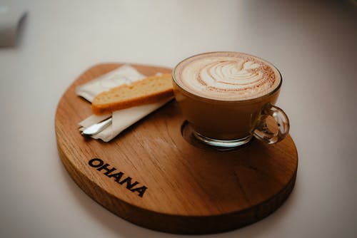 圆形透明玻璃咖啡杯，装满浓咖啡，圆形棕色木制托盘上饰有ohana浮雕 · 免费素材图片