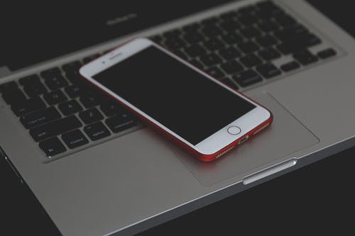 灰色便携式计算机上的银色iphone 6的浅焦点照片 · 免费素材图片