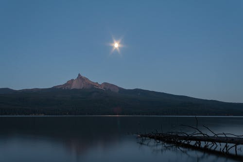 平静的水体旁的山 · 免费素材图片