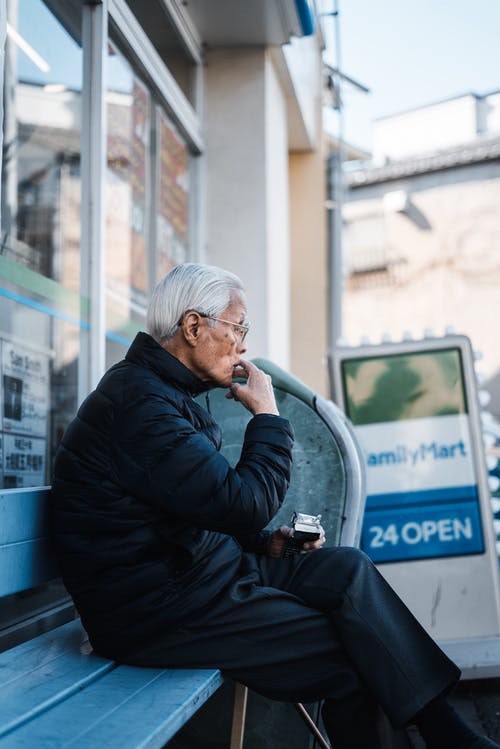 坐在木凳上的黑夹克的男人 · 免费素材图片