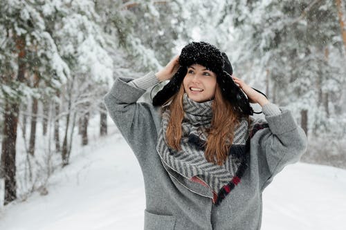 微笑的女士站在被雪覆盖的树木旁边 · 免费素材图片