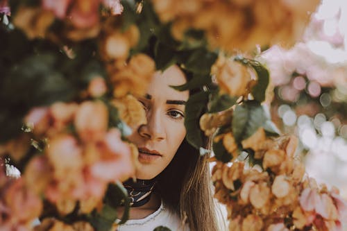 女人站在米色花瓣花下 · 免费素材图片