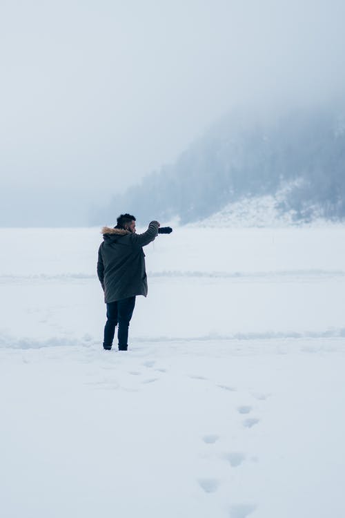 黑色大衣连帽衫站在雪地上的人 · 免费素材图片