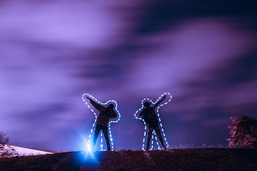 两人在夜间站在山上 · 免费素材图片