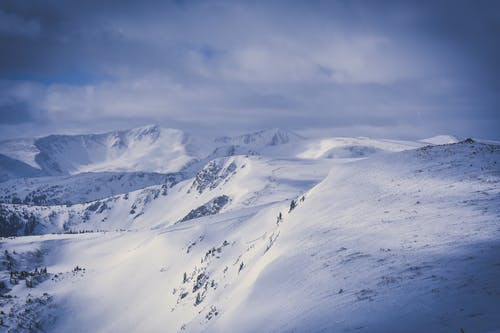 积雪覆盖的山脉上空的灰色多云的天空 · 免费素材图片