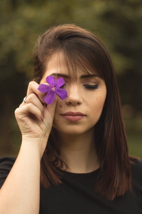 妇女的浅焦点照片在拿着紫色花的黑乘员组脖子衬衣的妇女 · 免费素材图片